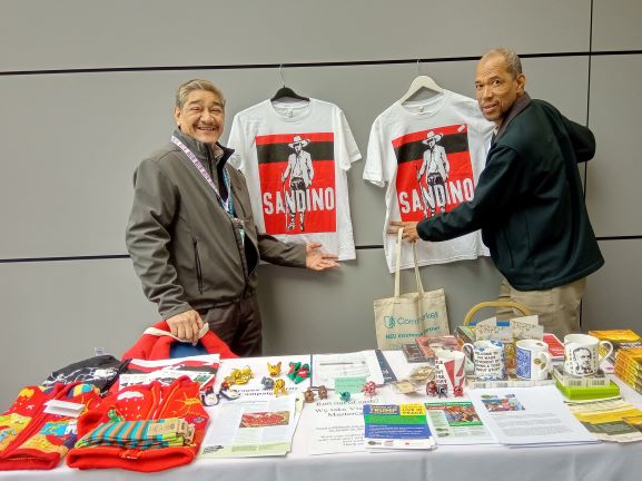 Jose Antonio and Johnny at NSCAG stall during NEU Conference with t-shirts of Augusto Cesar Sandino, national hero of Nicaragua